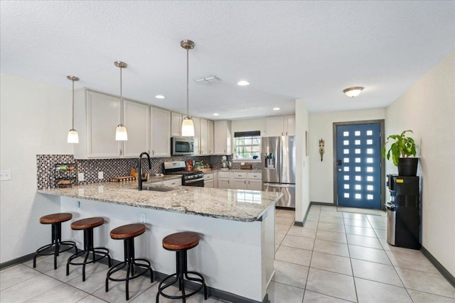 kitchen featuring appliances with stainless steel finishes, a sink, a peninsula, and decorative backsplash