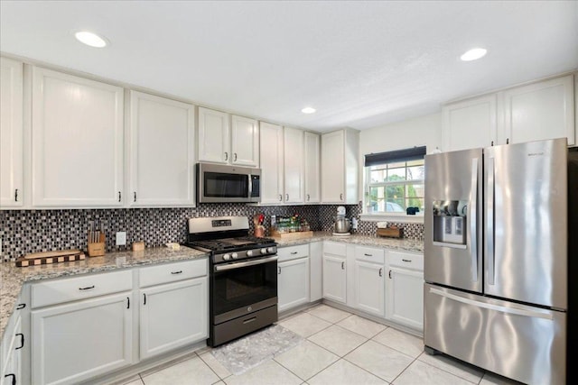 kitchen featuring white cabinetry, appliances with stainless steel finishes, backsplash, and light tile patterned flooring