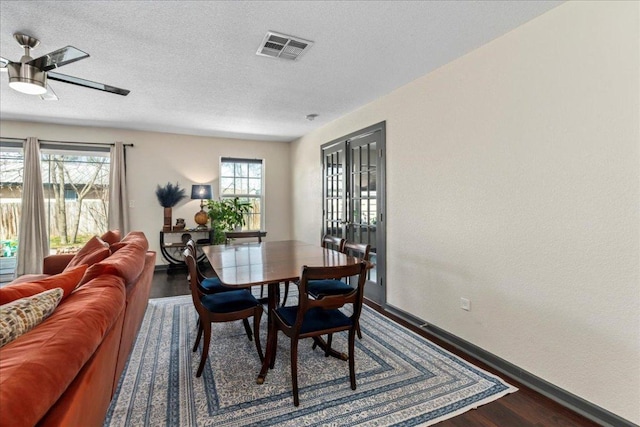 dining room featuring a textured ceiling, wood finished floors, visible vents, and a healthy amount of sunlight