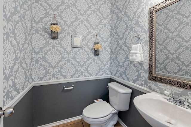 bathroom with baseboards, a sink, toilet, and tile patterned floors