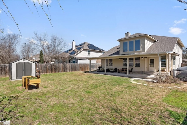 rear view of house featuring a yard, a patio, a storage unit, a fenced backyard, and an outdoor structure