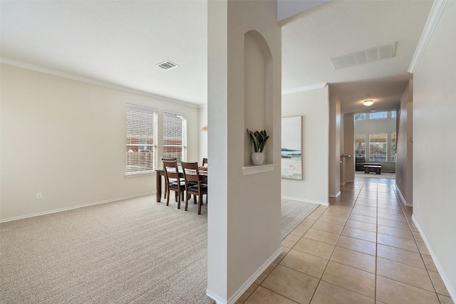 hallway featuring light carpet, ornamental molding, light tile patterned flooring, and visible vents