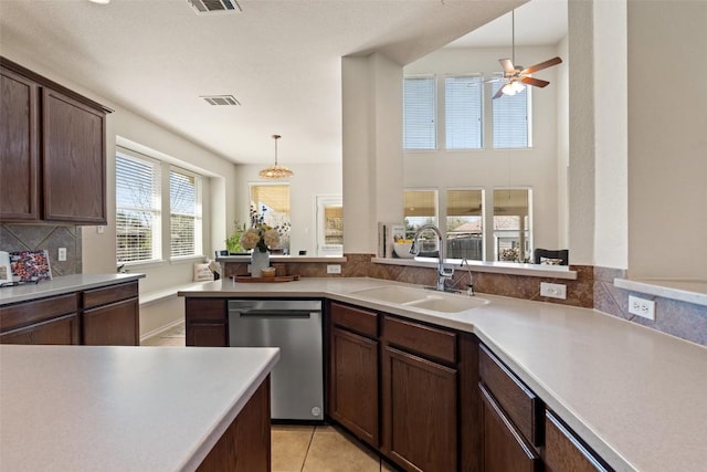 kitchen with light tile patterned floors, a sink, light countertops, backsplash, and dishwasher