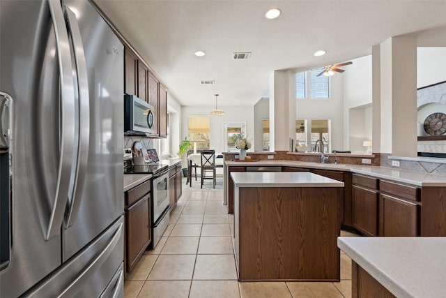 kitchen with light tile patterned floors, stainless steel appliances, a kitchen island, and visible vents