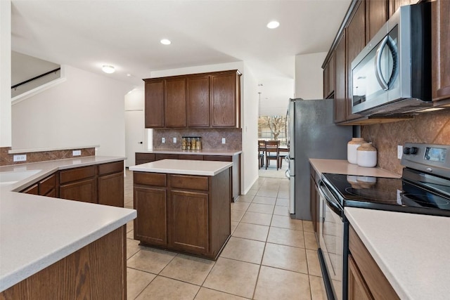 kitchen featuring tasteful backsplash, light countertops, appliances with stainless steel finishes, light tile patterned flooring, and a sink