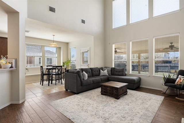 living area with ceiling fan, dark wood-type flooring, visible vents, and baseboards