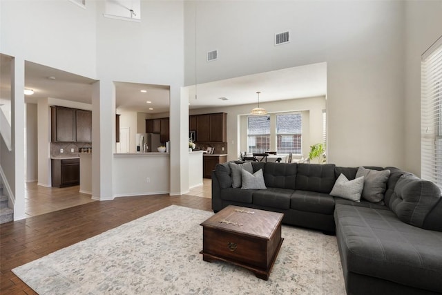 living area featuring light wood-style floors, visible vents, baseboards, and stairs