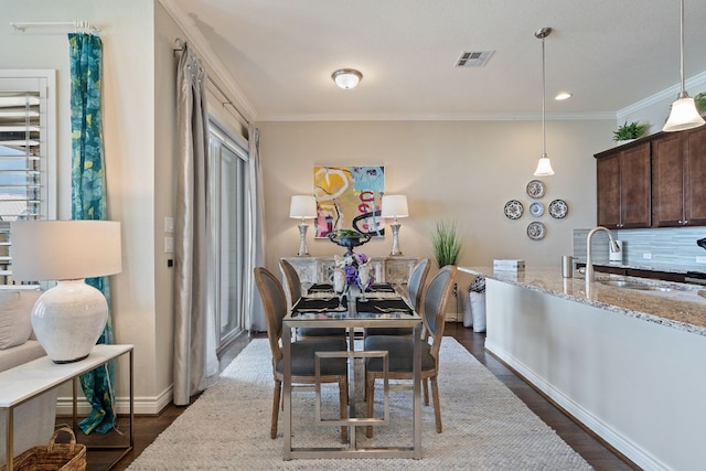 dining area with ornamental molding, dark wood-type flooring, visible vents, and baseboards