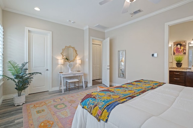 bedroom with ornamental molding, wood finished floors, visible vents, and baseboards