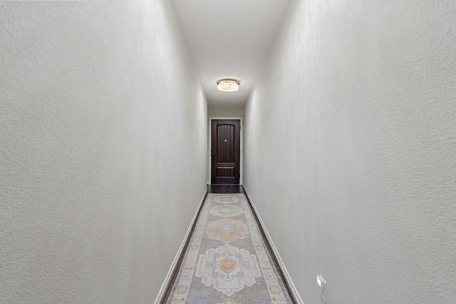 corridor with a textured wall and baseboards