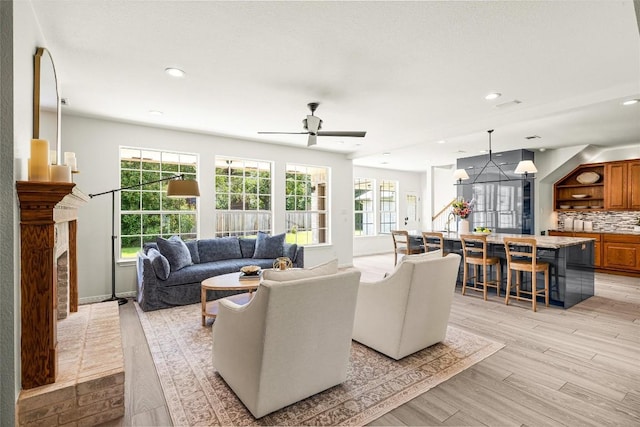 living area with recessed lighting, light wood-style flooring, a wealth of natural light, and a high end fireplace