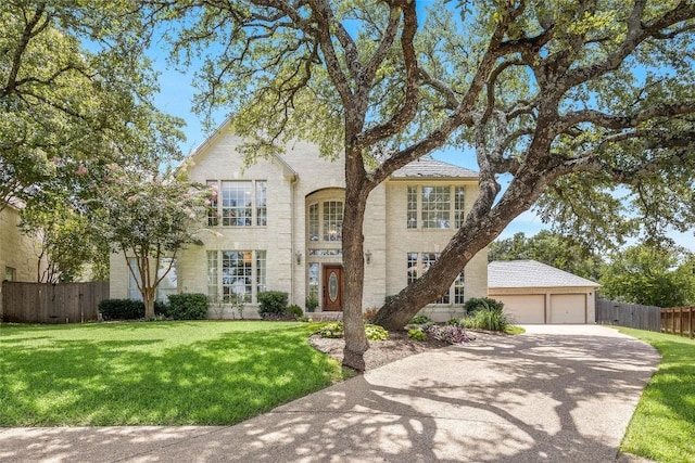 view of front facade with an attached garage, brick siding, fence, concrete driveway, and a front yard