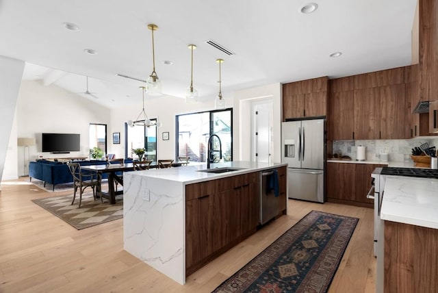 kitchen with light wood-style floors, modern cabinets, stainless steel appliances, and a sink