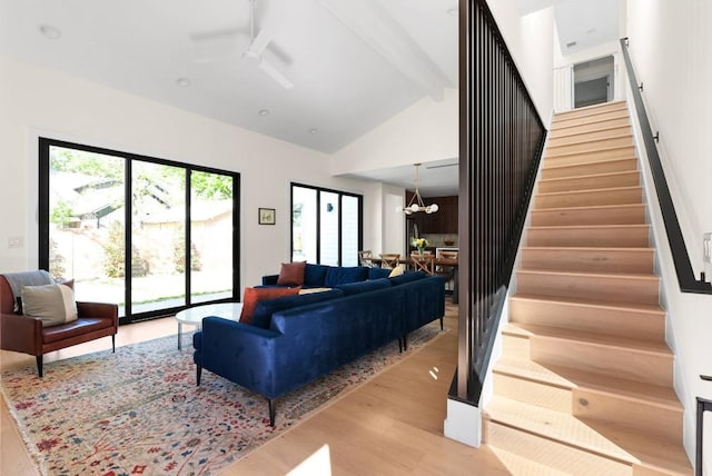 living room featuring stairs, beam ceiling, wood finished floors, high vaulted ceiling, and ceiling fan with notable chandelier