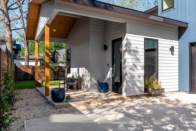 entrance to property featuring fence, board and batten siding, and a patio