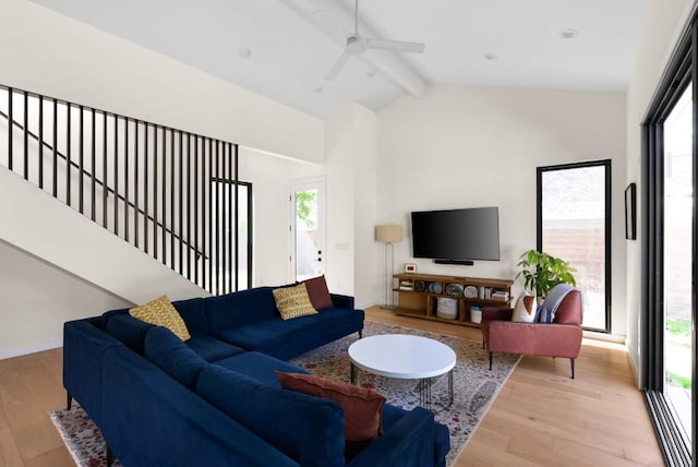 living area with stairs, beamed ceiling, wood finished floors, and baseboards