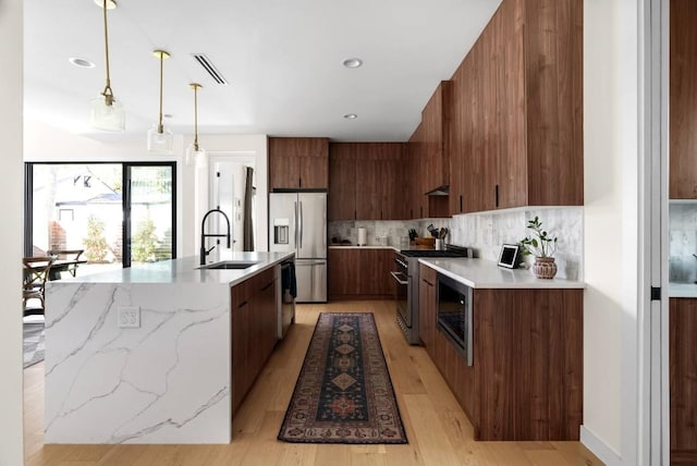 kitchen featuring tasteful backsplash, visible vents, modern cabinets, stainless steel appliances, and a sink