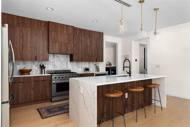 kitchen with light wood finished floors, tasteful backsplash, stainless steel appliances, and a sink