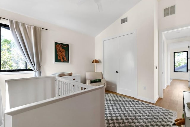 bedroom with a closet, multiple windows, visible vents, and wood finished floors