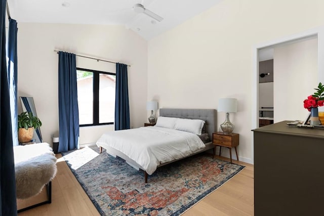 bedroom with a ceiling fan, lofted ceiling, and light wood-style flooring