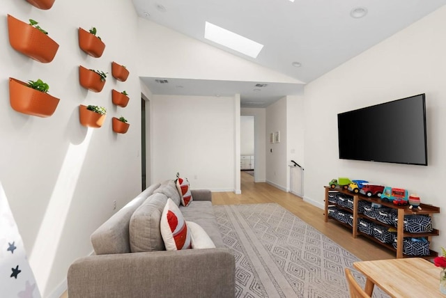 living room with lofted ceiling with skylight, light wood-style flooring, visible vents, and baseboards