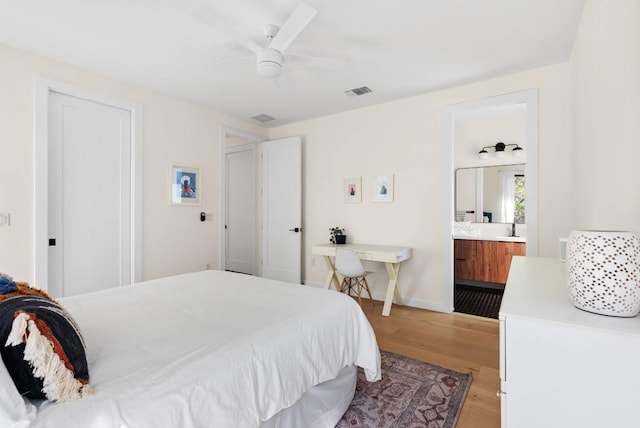 bedroom with visible vents, ensuite bathroom, ceiling fan, light wood-type flooring, and baseboards