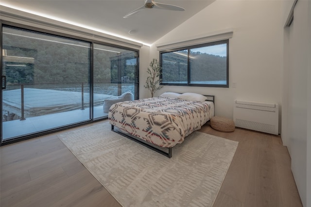 bedroom featuring vaulted ceiling, access to outside, wood finished floors, and a ceiling fan