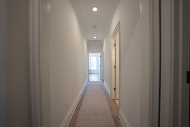 corridor with recessed lighting, wood finished floors, visible vents, baseboards, and ornamental molding