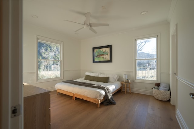 bedroom with baseboards, ornamental molding, ceiling fan, and wood finished floors