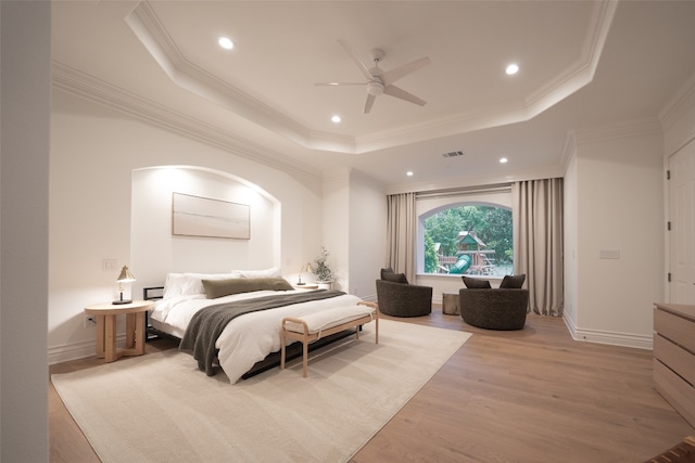 bedroom with light wood finished floors, visible vents, ornamental molding, a tray ceiling, and recessed lighting