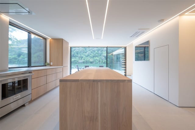 kitchen with a center island, light countertops, high end stainless steel range oven, light brown cabinets, and modern cabinets