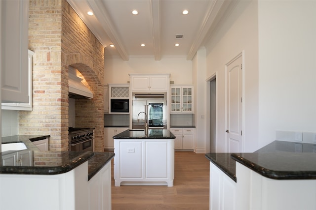 2301 Manana St, Austin, TX 78730 - kitchen with built in appliances, decorative backsplash, light wood finished floors, beamed ceiling, and a kitchen island with sink