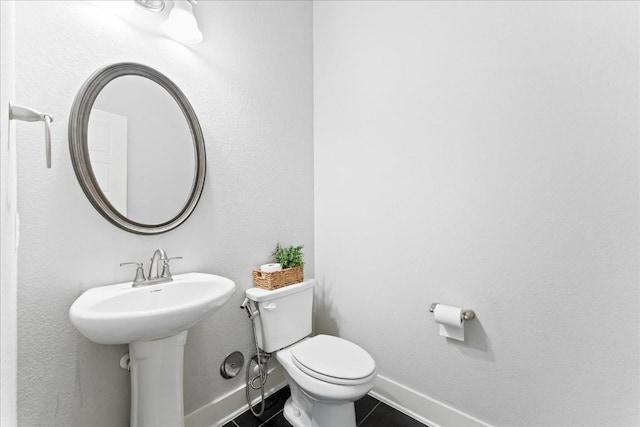 half bathroom featuring toilet, tile patterned flooring, and baseboards