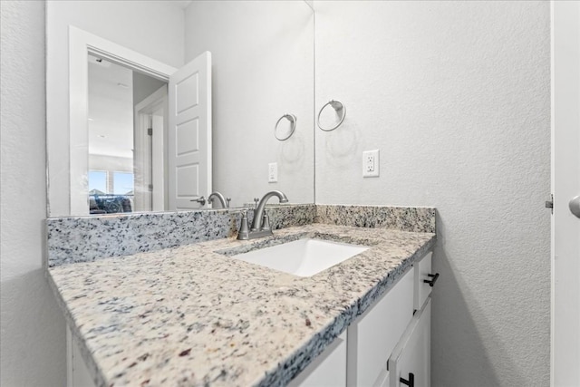 bathroom with a textured wall and vanity