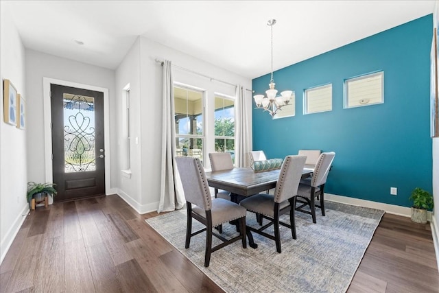 dining room with a notable chandelier, baseboards, and wood finished floors