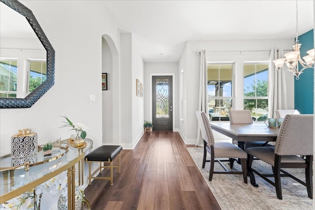 entrance foyer featuring a wealth of natural light, a notable chandelier, baseboards, and wood finished floors