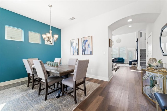 dining room with arched walkways, visible vents, baseboards, stairs, and dark wood-style floors