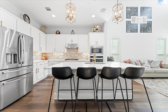 kitchen featuring stainless steel appliances, an inviting chandelier, visible vents, and under cabinet range hood