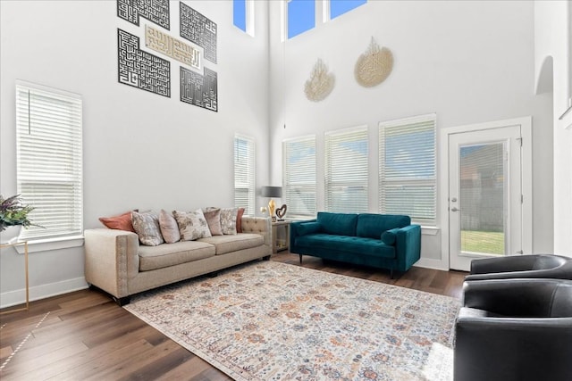 living area featuring a high ceiling, baseboards, and wood finished floors