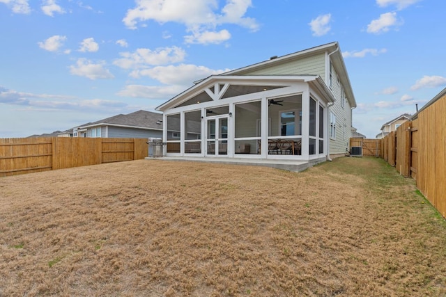 rear view of house featuring a lawn, cooling unit, a sunroom, and a fenced backyard