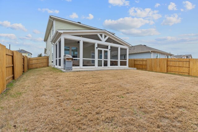 back of house featuring a sunroom, a fenced backyard, and a lawn