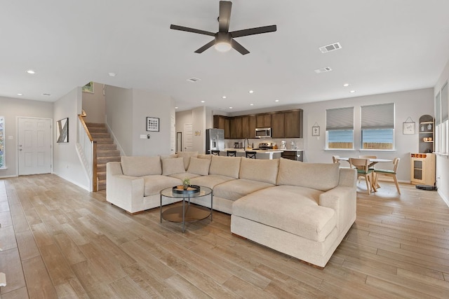 living area featuring light wood finished floors, stairs, a ceiling fan, and recessed lighting