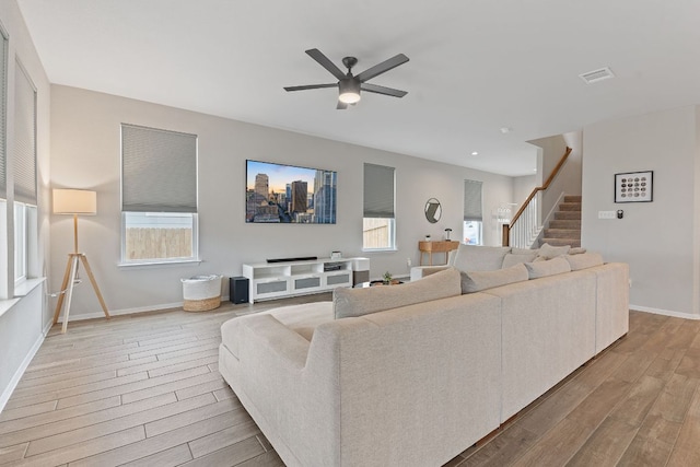 living room with stairway, wood finished floors, visible vents, and baseboards