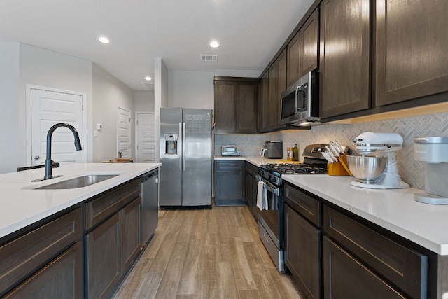 236 Stein Rd, Georgetown, TX 78626 - kitchen featuring appliances with stainless steel finishes, a sink, dark brown cabinetry, light wood finished floors, and light countertops