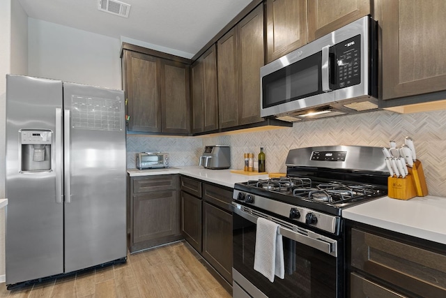 kitchen with backsplash, visible vents, stainless steel appliances, and dark brown cabinets