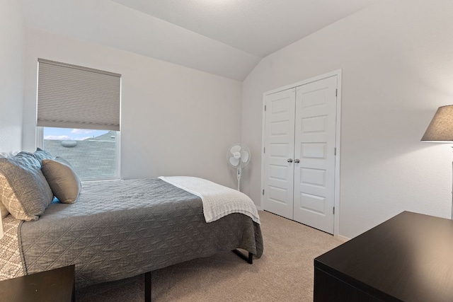 bedroom featuring a closet, light colored carpet, and vaulted ceiling