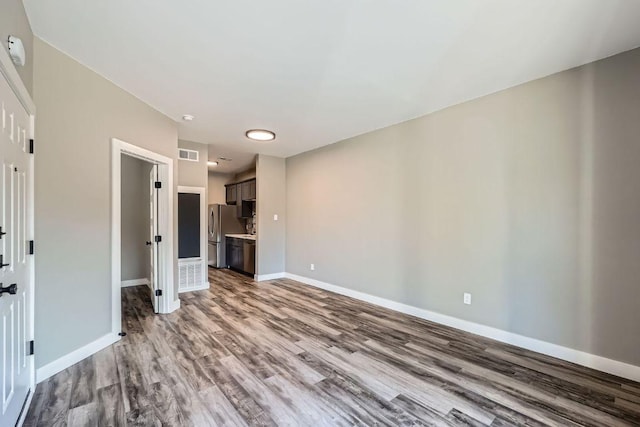 unfurnished living room with visible vents, baseboards, and wood finished floors