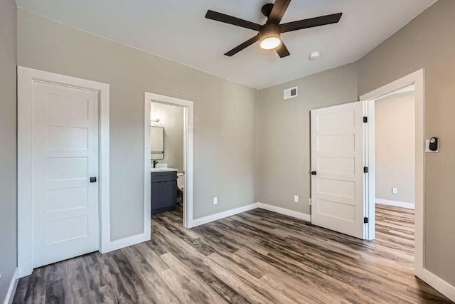 unfurnished bedroom with dark wood-style flooring, a sink, visible vents, and baseboards