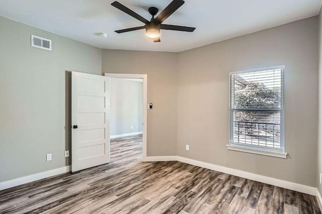 unfurnished room with baseboards, visible vents, ceiling fan, and wood finished floors