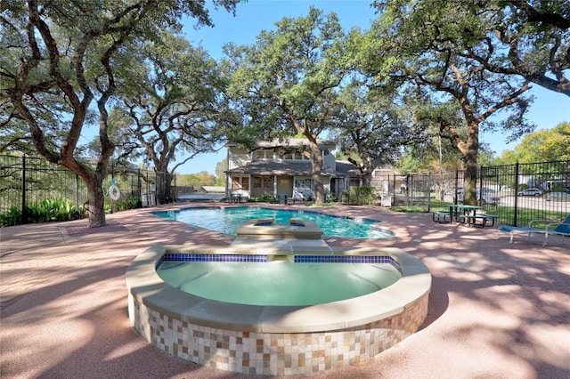 view of pool with an in ground hot tub, a patio, fence, and a fenced in pool